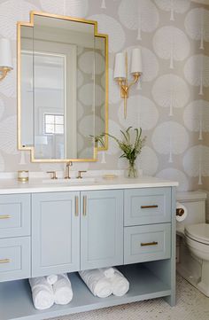 a bathroom with blue cabinets and gold accents