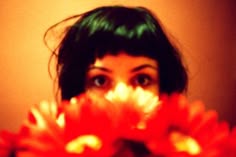 a woman with green hair holding flowers in front of her face