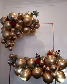 a wreath made out of gold balls and roses on a wall with a red rose in the middle