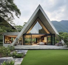 a triangular shaped house in the middle of a lush green field