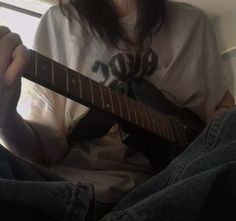 a person sitting down with a guitar in their lap