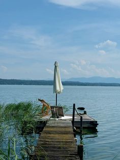 an umbrella and chair on a dock in the water