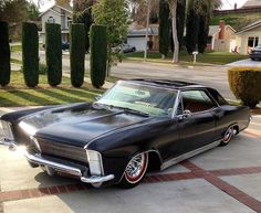 an old black car is parked in the driveway