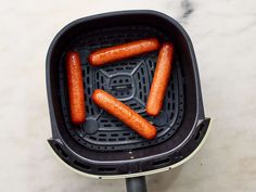 four hot dogs are being cooked in an air fryer
