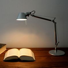 an open book sitting on top of a wooden table next to a light that is turned on