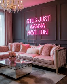 a living room filled with furniture and a pink neon sign above the couch that says girls just wanna have fun