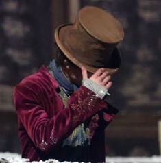 a man in a red coat and hat covers his face with his hands