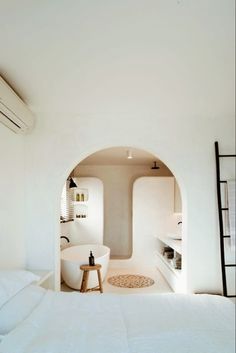a white bed sitting in a bedroom next to a sink and oven on top of a wall