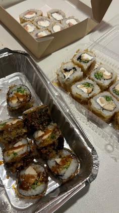 there are many sushi rolls in the trays on the table and one is ready to be eaten