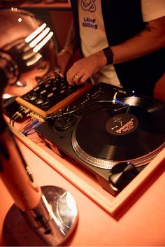 a dj mixing music on top of a turntable in front of a record player
