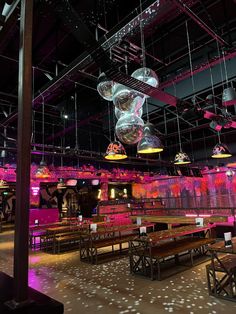 the inside of a restaurant with pink lights and chandeliers hanging from the ceiling
