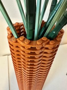an orange vase filled with lots of green straws on top of a white counter