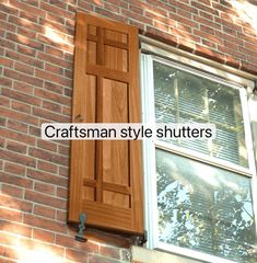 an open window on the side of a brick building with shutters and wood slats