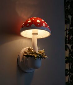 a mushroom shaped light is on the wall next to a potted plant with plants growing out of it