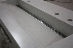 the sink is made out of concrete and steel grates are visible in this image