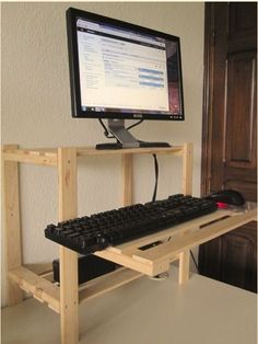 a computer monitor sitting on top of a wooden stand next to a keyboard and mouse