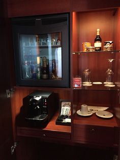 there is a coffee maker and other items on the shelf in this small bar area