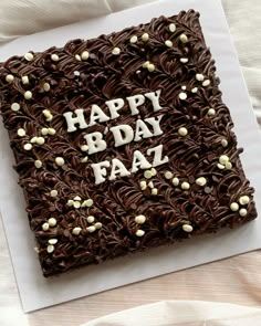 a birthday cake with chocolate frosting and white sprinkles on it that says happy b day faz