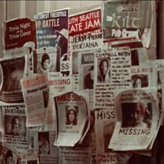 many newspapers are hanging on the wall in front of a building with posters attached to it