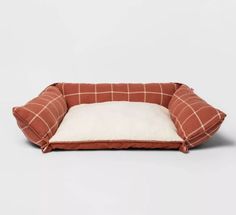 a brown and white dog bed with a pillow on it
