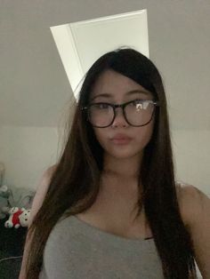 a woman with glasses is taking a selfie in front of the camera while wearing a tank top