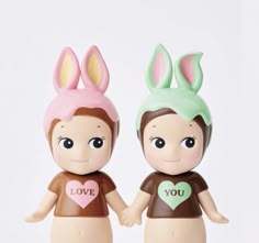 two toy figurines with bunny ears on their heads, one holding the other's hand