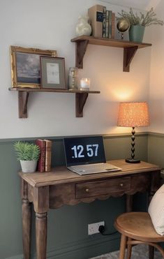 a wooden desk with a laptop on top of it next to a chair and lamp