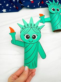 a hand holding up a paper doll with the statue of liberty on it