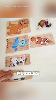 a person holding up four wooden puzzles with cartoon characters on them and the words puzzles written below it