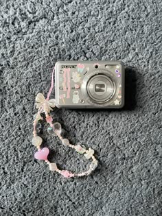 a camera is laying on the ground next to a beaded necklace