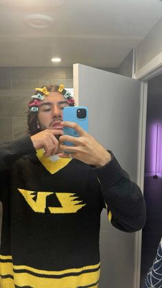 a man taking a selfie in front of a mirror wearing a yellow and black sweater