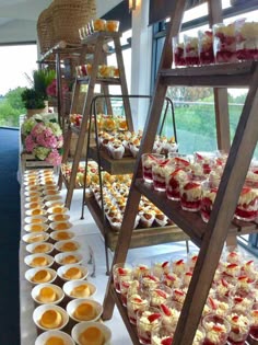 many desserts are displayed on wooden trays in front of windows and flowers behind them
