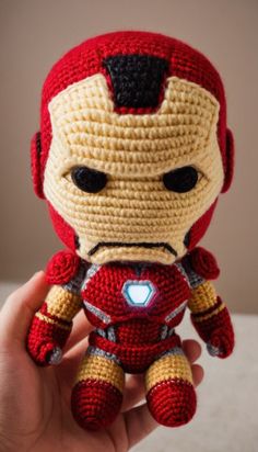a crocheted iron man doll is held up in the palm of someone's hand