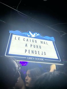 people are standing under a marquee sign in the dark