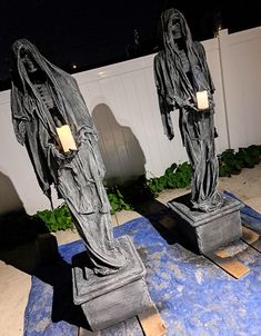 two statues that are standing next to each other on a blue rug in front of a white fence