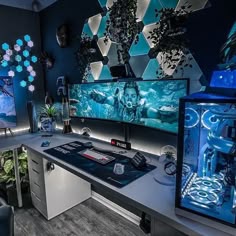 a desk with two computer monitors on top of it next to a plant filled wall