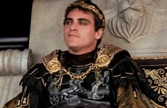 a man dressed in armor sitting next to a statue