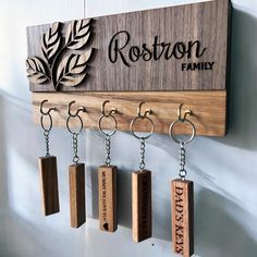 a wooden key holder with six wood blocks hanging from it's hooks and the name rostron family engraved on them