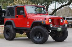 a red jeep is parked in a parking lot