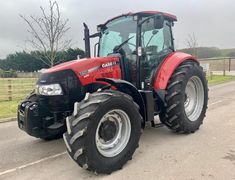 a red tractor is parked on the side of the road
