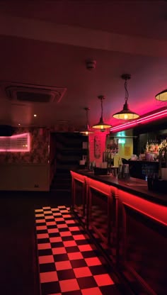 a dimly lit bar with checkered flooring and neon lights
