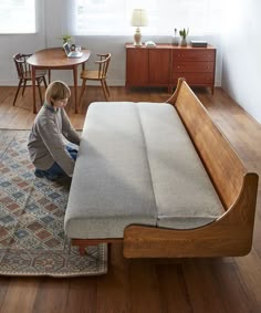 a little boy sitting on the floor next to a bed with a mattress in it