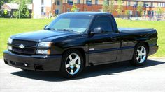 a black pickup truck parked in a parking lot next to a building and grass area