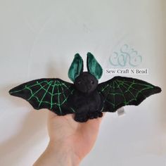 a hand holding a black bat with green wings
