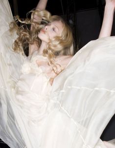 a woman in a white dress is laying on the floor with her arms up and legs spread out