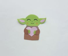 a cut out of paper with a baby yoda holding a heart on it's chest