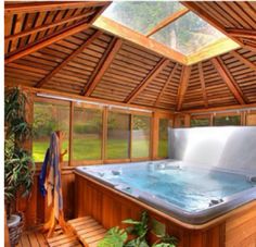 a hot tub inside of a wooden structure with plants in the corner next to it