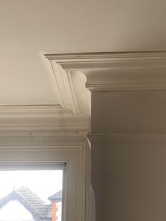 the corner of a room with a window and white molding on the ceiling above it