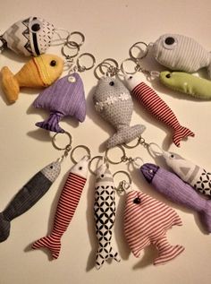 a bunch of fish key chains that are on a white table with black and red stripes