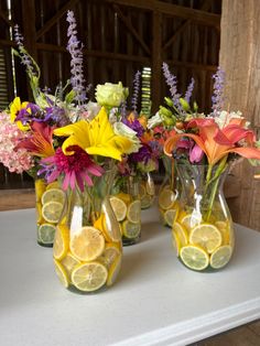 three vases filled with lemon slices and flowers on top of a white countertop